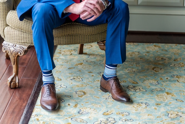 Closeup of the legs of the groom sitting on the chair and waiting for the ceremony