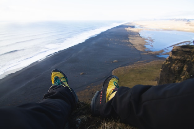 Closeup of legs of a person sitting on the rock with the sea in Iceland