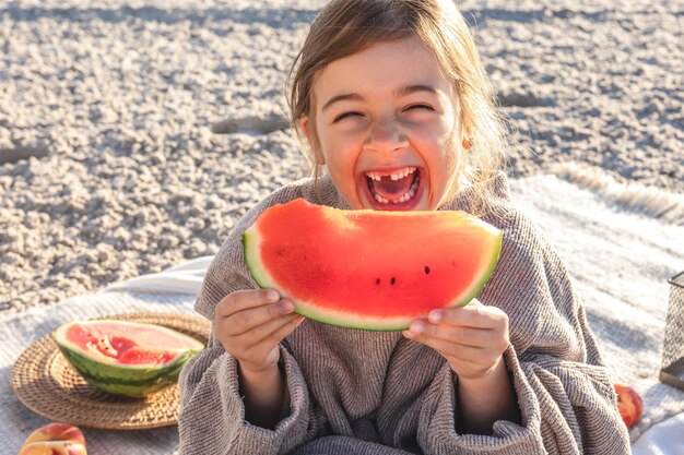 근접 촬영 어린 소녀는 해변에서 수박을 먹는다