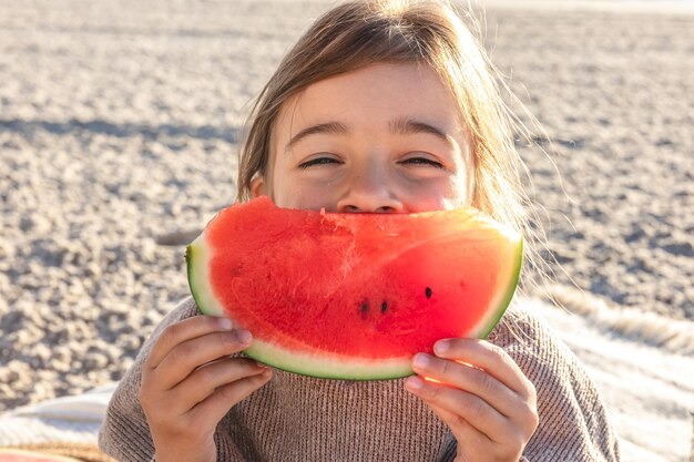 Foto gratuita la bambina del primo piano mangia l'anguria sulla spiaggia