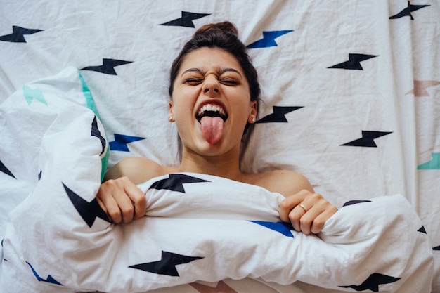 Closeup of Lovely young Woman Lies in Bed Covered with Blanket.