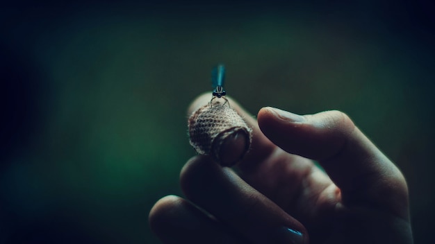 Closeup macro shot of a firefly on a man's hand with dark green background