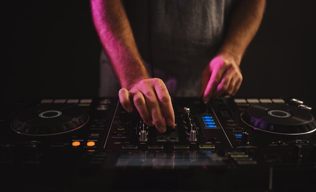 Closeup of a male DJ working under the lights against a dark background in a studio