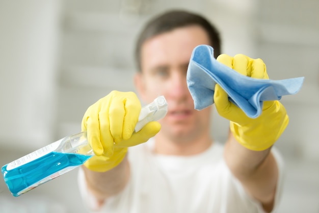 Free photo closeup of male hands in gloves holding spray and rug