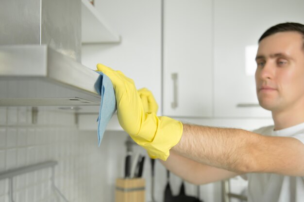 Closeup of male hands in rubber gloves cleaning extractor hood
