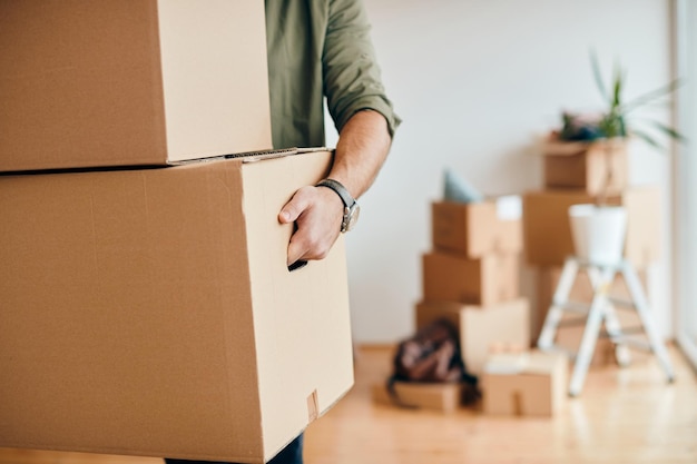 Closeup of man carrying cardboard boxes while relocating into new apartment