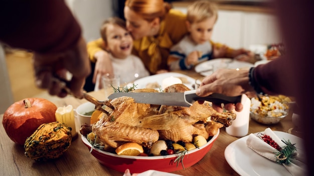 Closeup of man carving Thanksgiving turkey during family dinner at home