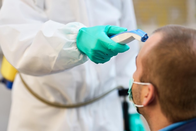 Closeup of man getting his temperature with infrared thermometer during coronavirus epidemic