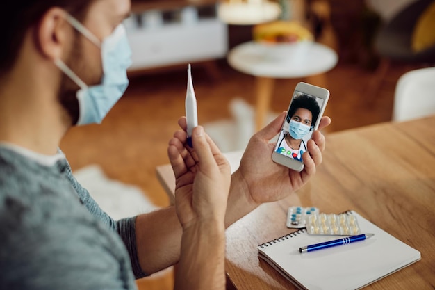 Closeup of man having online consultations with a doctor about his fever during coronavirus pandemic