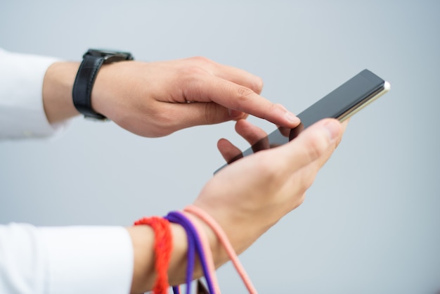 Closeup of man holding shopping bags and using smartphone