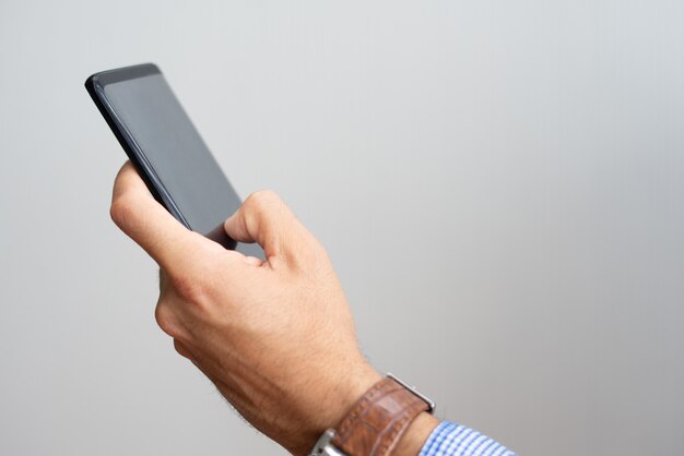 Closeup of man holding smartphone and touching its screen
