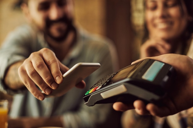 Free photo closeup of man making contactless payment with smart phone