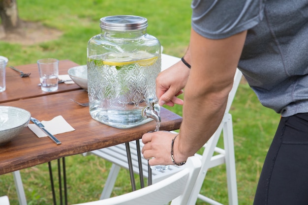 Closeup of man pouring lemonade from dispenser outdoors