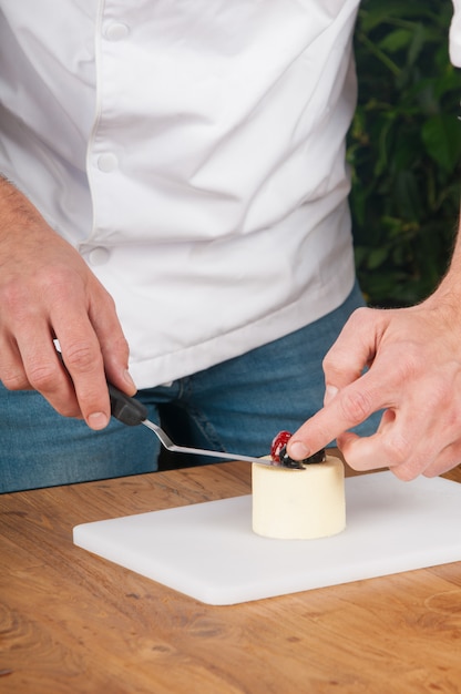 Closeup of man putting berries on peace of ice-cream at table