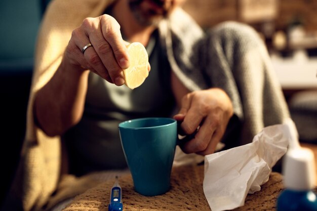 Closeup of man squeezing lemon into a tea cup