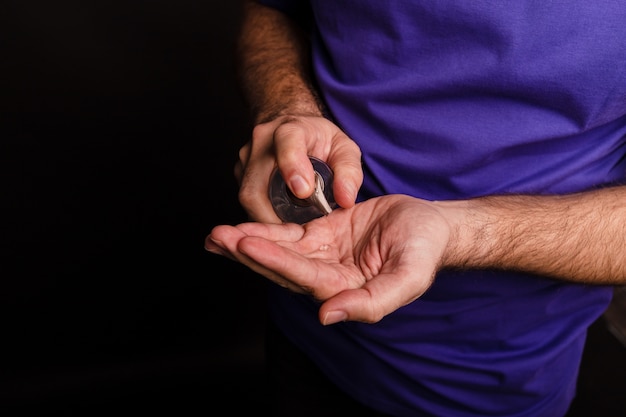 Closeup of a man using a hand sanitiser on black