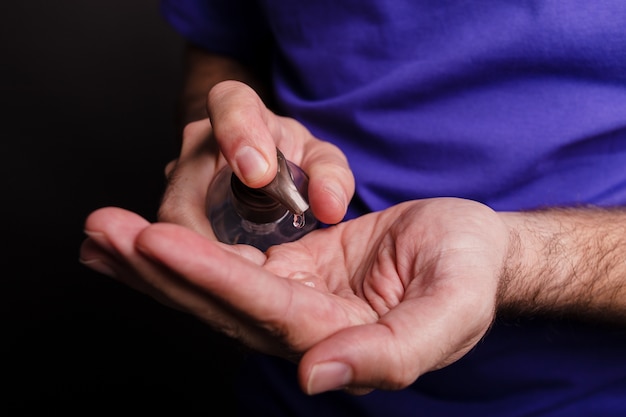 Closeup of a man using a hand sanitiser on black