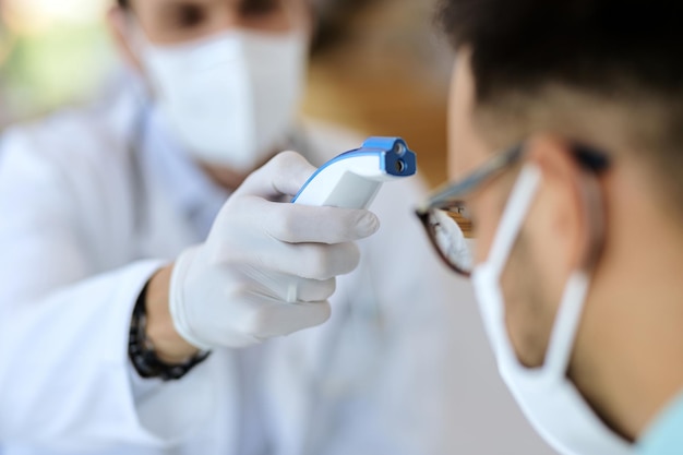 Closeup of measuring temperature with infrared thermometer at medical clinic