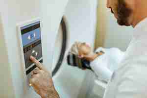 Free photo closeup of medical technician starting mri scan examination of a patient in the hospital
