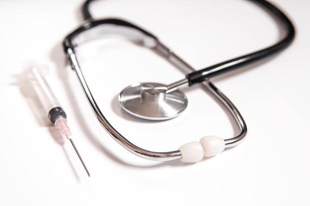 Closeup of medicines, syringes and stethoscope. Clean and bright health care image. Plastic Syringe with Needle Isolated on the White Background