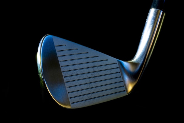 Closeup of a metal golf club on black