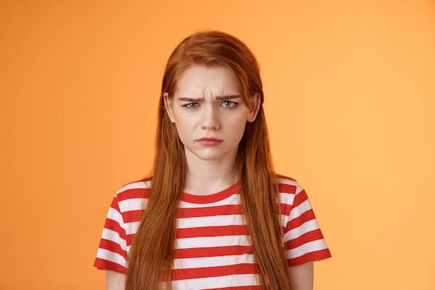 Closeup moody upset childish redhead girl sulking unfair situation frowning upset complaining disapp...