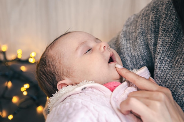 closeup of a newborn baby girl falls asleep in her mothers arms