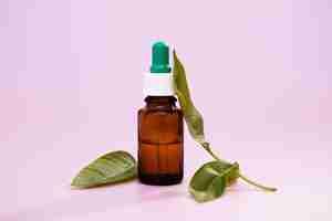 Бесплатное фото Крупный план экстрактов лекарственных листьев в бутылке с лекарством на розовом фоне