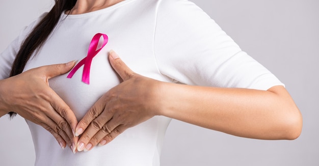 乳がん​の​原因​を​サポートする​ために​女性​の​胸​に​ピンク​の​バッジ​リボン​の​クローズアップ