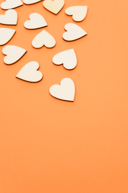Бесплатное фото Крупным планом сердечки деревянной формы на оранжевой поверхности - место для текста