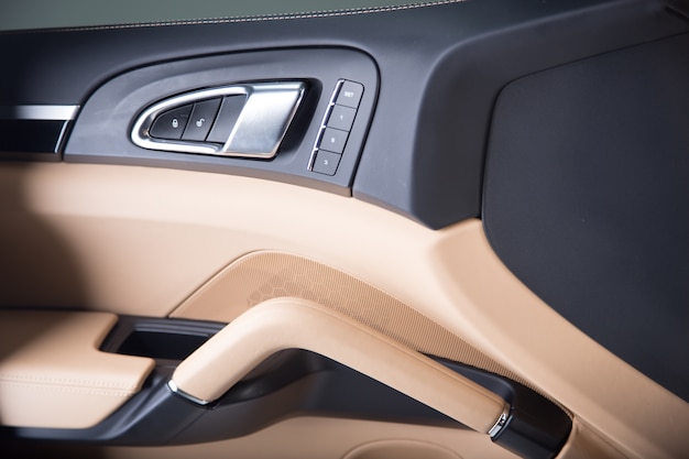 Closeup of an open beige door of a modern luxury car under the lights