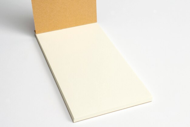 Крупный план раскрытого дневника при книга в твердой обложке картона и пустые страницы изолированные на белизне.
