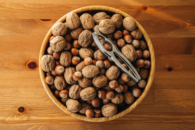 Closeup overhead shot of nuts with a nutcracker in a wooden plate on a wooden table