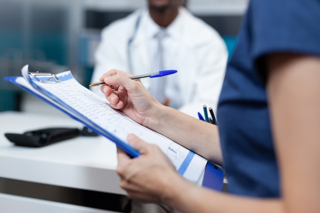 Closeup of patient mother writing medical information on document