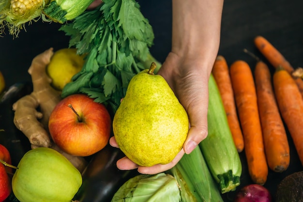 Free photo closeup an pear in a female hand on a blurred background with vegetables