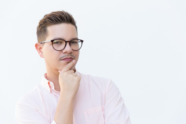 Closeup of pensive serious guy in eyewear touching chin