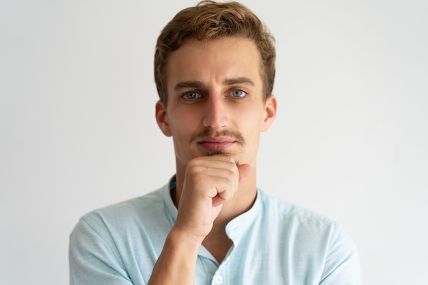 Closeup of pensive serious guy in white casual shirt. 