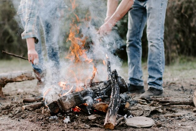 Closeup of people making a bonfire in the forest
