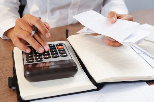 Closeup of person calculating bills on calculator