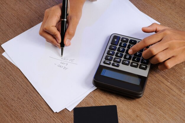 Closeup of person calculating on calculator and writing