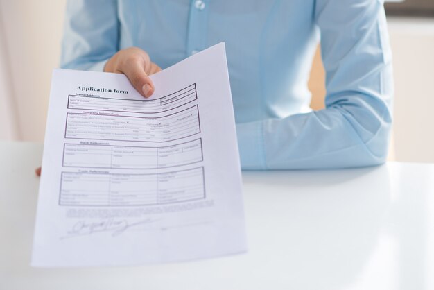 Closeup of person giving signed application form to viewer