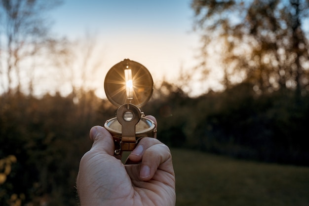 Closeup of a person holding a compass with sun shining through the hole