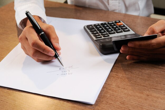 Closeup of person holding credit card and calculating