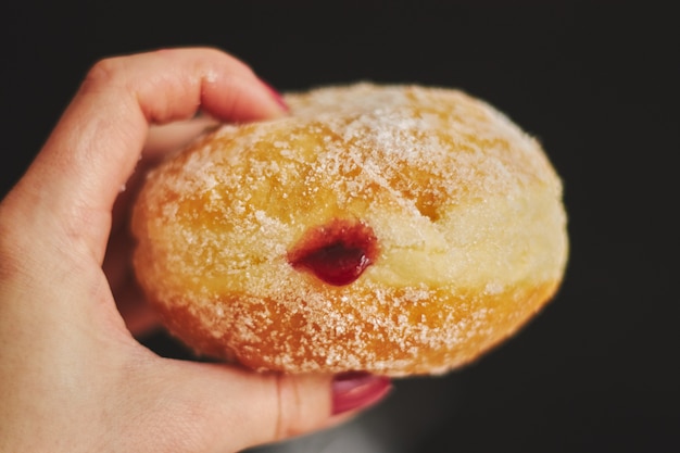 Closeup of a person holding a fluffy doughnut under the lights