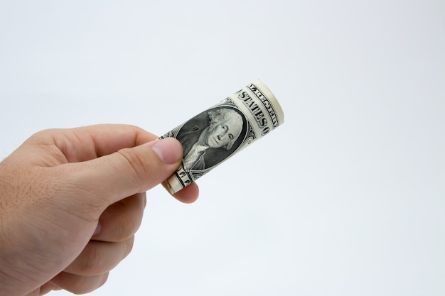 Free photo closeup of a person holding a folded dollar bill on a gray wall