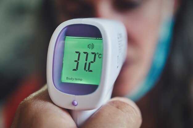 Closeup of a person measuring temperature with a digital thermometer