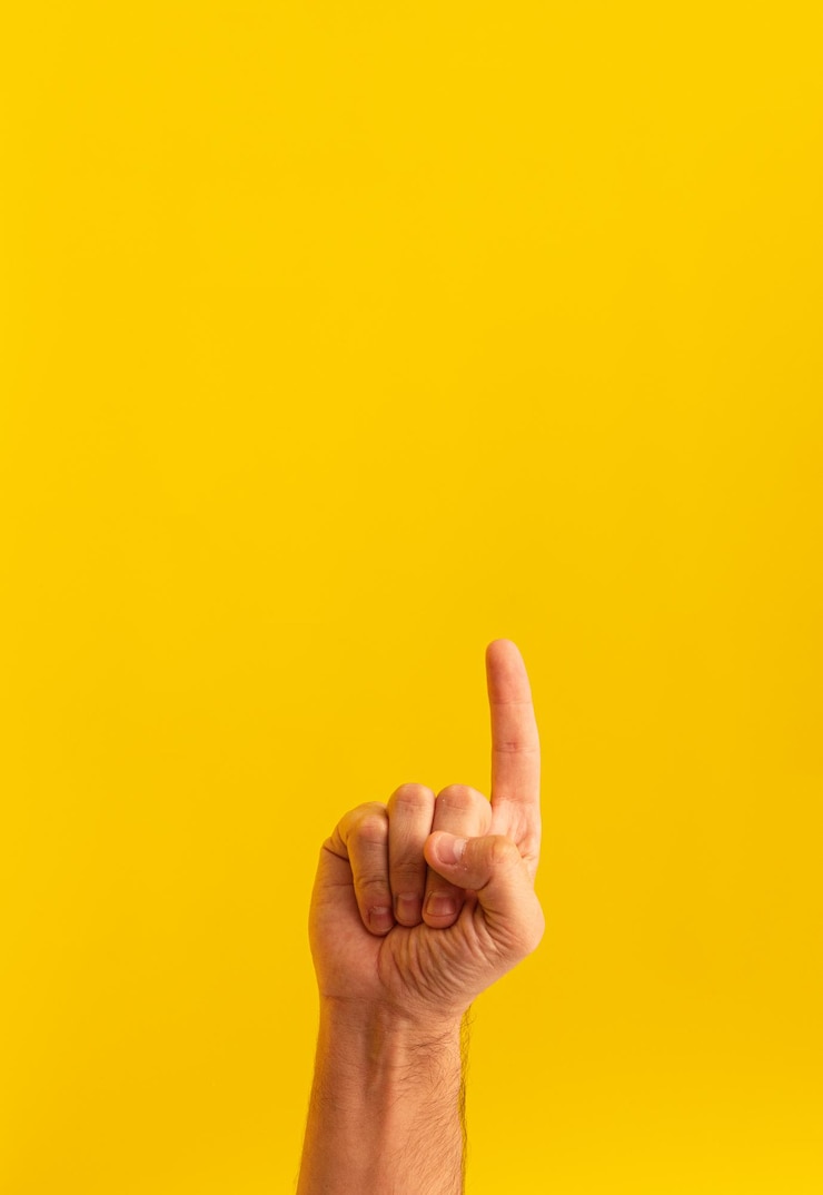 Free Photo closeup of a person pointing up isolated on a yellow background with space for text