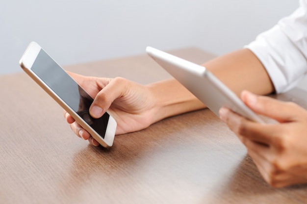 Closeup of person using tablet computer and smartphone