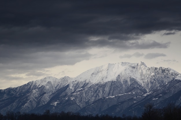 Closeup pf snow-capped mountains in the Alps with dark clouds