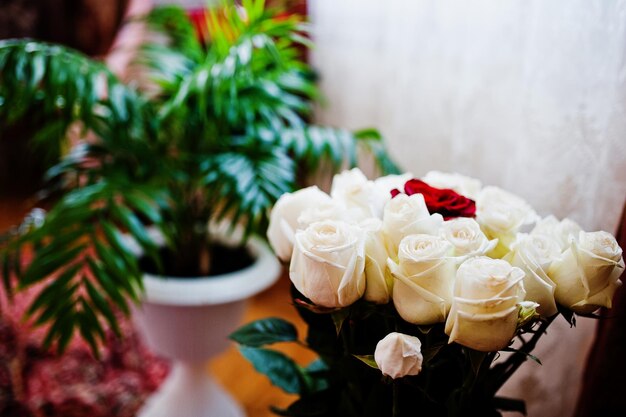 Closeup photo of a bouquet made out of white roses and one red rose